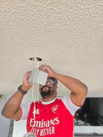 Calgary electrician Yaya smiling while completing ceiling light installation