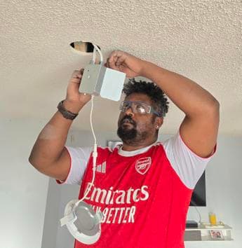 Experienced Calgary electrician Yaya installing ceiling light fixture
